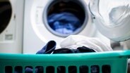 Eine voller Wäschekorb steht vor einer Waschmaschine. © picture alliance/Wedel/Kirchner-Media Foto: Wedel