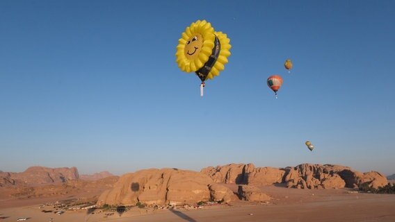 Heißluftballons schweben über Felsen in einer Wüste in Jordanien. © Tobias Landmann Foto: Tobias Landmann