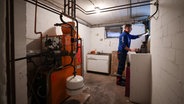 Ein Mitarbeiter eines Diesel- und Heizöl-Unternehmens prüft die beiden Kunststofftanks einer Heizung in einem Heizungskeller bei der Heizöllieferung für ein Einfamilienhaus. © dpa Foto: Christian Charisius