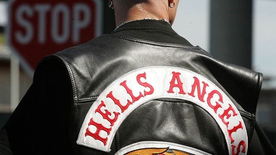 Ein Rocker mit einer Hells Angels Jacke steht an einem Stoppschild. © picture alliance / ZB Foto: Robert Michael