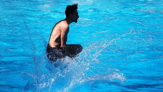 Ein Mann springt in ein Schwimmbecken. © picture alliance/dpa/Julian Weber Foto: Julian Weber