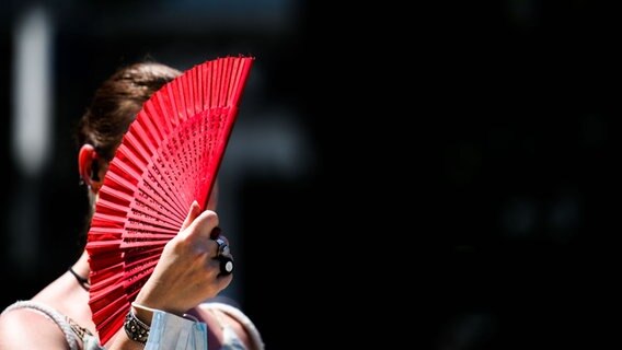 Eine Frau fächert sich bei Hitze kühle Luft zu. © picture alliance/dpa | Julian Stratenschulte Foto: Julian Stratenschulte