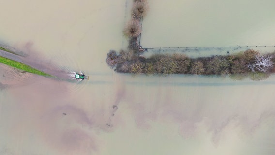 Ein Traktor fährt auf einem Feldweg zwischen überfluteten Feldern © dpa-Bildfunk Foto: Julian Stratenschulte/dpa