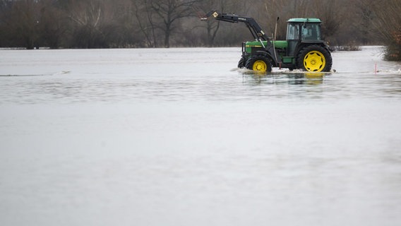 Ein Traktor fährt auf überfluteten Feldern in der Leinemasch in der südlichen Region Hannover. © dpa Foto: Julian Stratenschulte