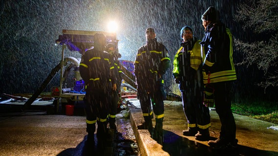 Einsatzkräfte von THW und Feuerwehr stehen in Wienhausen an einer Pumpe. © dpa Foto: Philipp Schulze