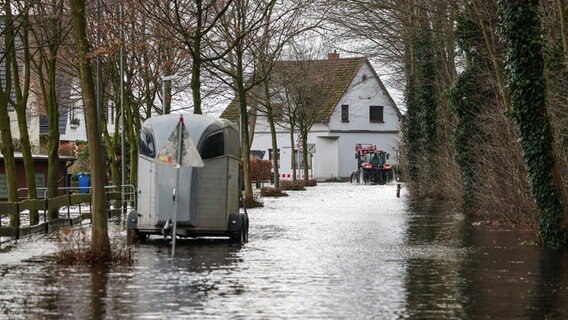 Ein Traktor fährt durch eine überflutete Wohnstrasse an der Wörpe in Lilienthal. © dpa Foto: Focke Strangmann