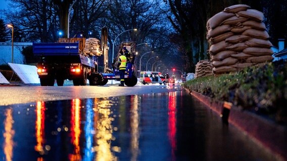 Einsatzkräfte des Technischen Hilfswerks laden bei Regen zahlreiche Sandsäcke an der Sandkruger Straße im Stadtteil Bümmerstede in Oldenburg ab. © picture alliance/dpa | Hauke-Christian Dittrich Foto: Hauke-Christian Dittrich