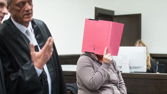 Die Angeklagte Angelika W. steht neben ihren Rechtsanwälten und verdeckt ihr Gesicht mit einer Mappe. © dpa-Bildfunk Foto: Bernd Thissen