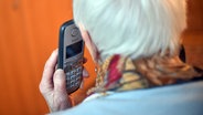Eine Seniorin hält einen Telefonhörer an ihr Ohr. © picture alliance/dpa/Britta Pedersen Foto: Britta Pedersen