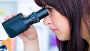 Junge Frau schaut in ein Mikroskop © Fotolia.com Foto: science photo