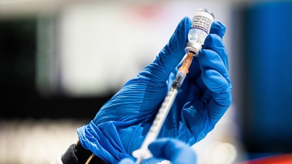 Zwei Hände ein Einweghandschuhen ziehen eine Spritze mit Corona-Impfstoff auf. © picture alliance Foto: Michael Matthey