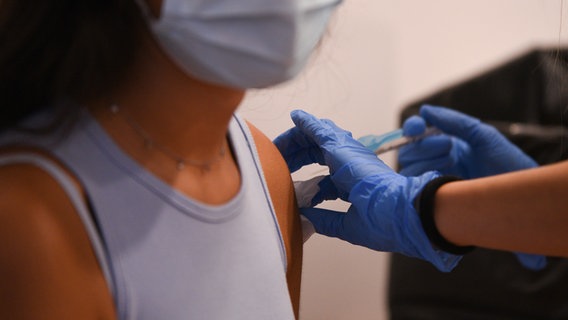 Eine junge Frau mit Maske wird am Oberarm geimpft. © picture alliance/dpa/EUROPA PRESS Foto:  Jorge Gil