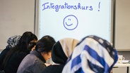 Frauen mit und ohne Kopftuch sitzen in einem Klassenraum. Auf einer Tafel steht Integrationskurs. © NDR Foto: Julius Matuschik