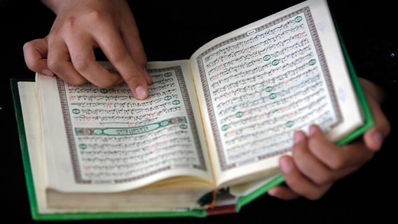 Hände halten einen aufgeschlagenen Koran.  Foto: Epa / Ali Ali