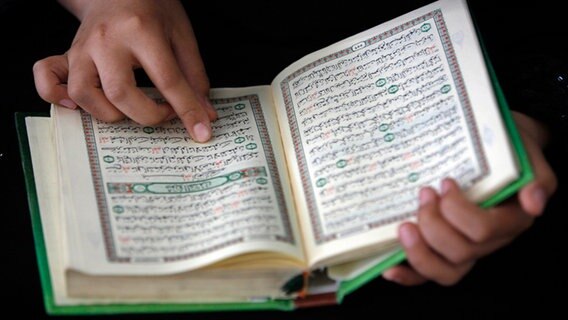 Hände halten einen aufgeschlagenen Koran. © dpa-Bildfunk Foto: Epa / Ali Ali