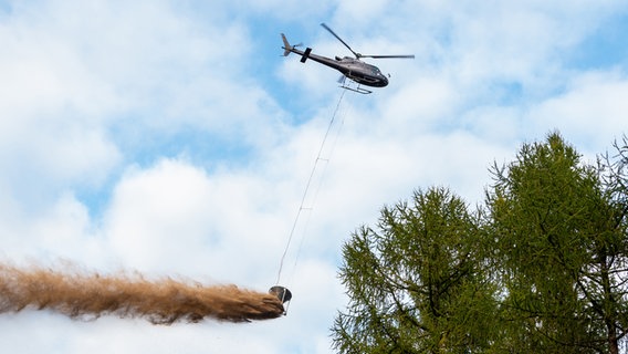 Ein Hubschrauber verteilt Kalk über einer Waldfläche. © picture alliance/dpa/Philipp Schulze Foto: Philipp Schulze
