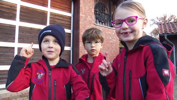 Drei Mitglieder der Kinderfeuerwehr stehen nebeneinander. © NDR 