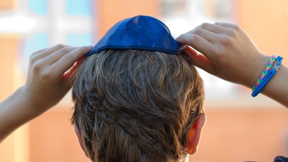 Ein Junge setzt sich eine Kippa auf den Kopf. © picture alliance/dpa Foto: Daniel Bockwoldt