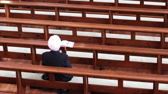 Eine Frau sitzt allein auf einer Kirchenbank. © picture alliance / Eibner-Pressefoto | Fleig / Eibner-Pressefoto 