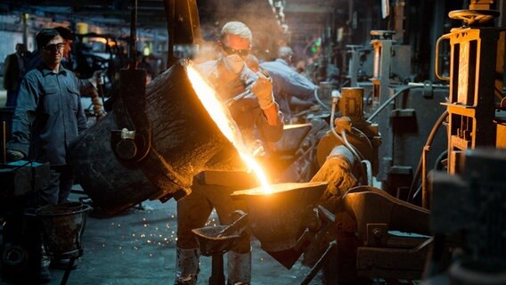 Ein Mitarbeiter gießt flüssiges Gusseisen im Werk eines Autozulieferers. © picture alliance/dpa Foto: Julian Stratenschulte