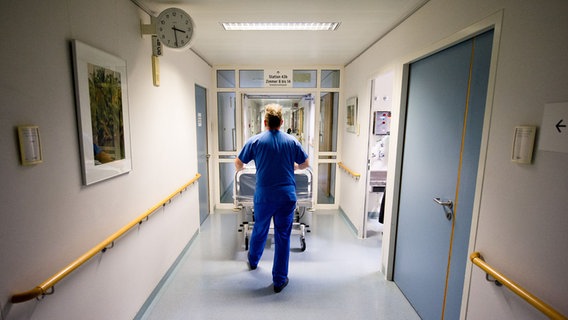Ein Krankenpfleger schiebt ein Bett durch eine Tür im Krankenhaus. © picture alliance / dpa | Daniel Bockwoldt Foto: Daniel Bockwoldt