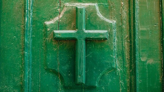 Ein Kreuz an einer Kirchentür. © picture alliance/Zoonar/Nadtochiy.com 