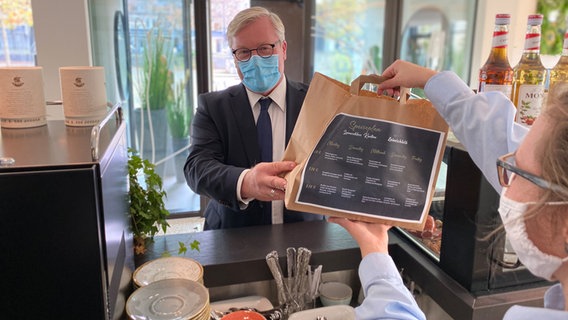 Wirtschaftsminister Bernd Althusmann (CDU) nimmt in einem Restaurant eine Takeaway-Bestellung in Empfang. © MW 