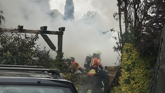 Zwei Feuerwehrleute mit Helm und Atemschutzgerät vor dichten Rauchschwaden. © Feuerwehr Braunschweig 