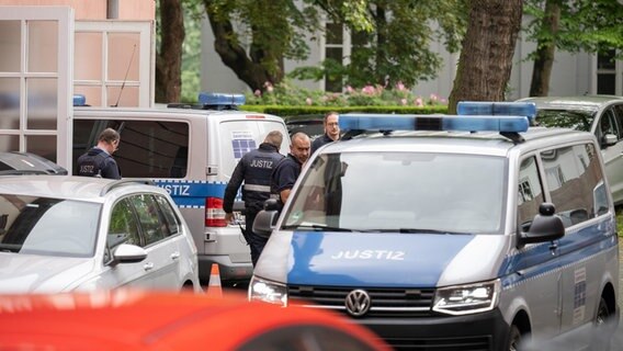 Zwei Fahrzeuge der Justiz, in denen jeweils Angeklagte saßen, fahren vor Prozessbeginn gegen Mitglieder der Gruppierung "Vereinte Patrioten" vor dem Oberlandesgericht Koblenz in einen Innenhof. © dpa Foto: Sebastian Gollnow