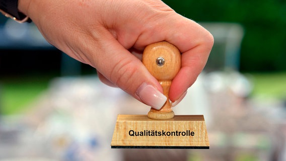 Ein Frau hat einen Stempel mit der Aufschrift "Qualitätskontrolle" in der Hand © picture alliance / blickwinkel/McPHOTO/K. Steinkamp | McPHOTO/K. Steinkamp Foto: picture alliance / blickwinkel/McPHOTO/K. Steinkamp | McPHOTO/K. Steinkamp