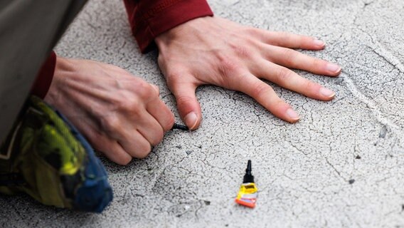 Eine Person klebt ihre Hand auf den Asphalt. © picture alliance/dpa | Matthias Balk Foto: Matthias Balk