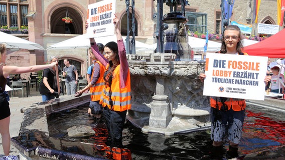 Klima-Aktivisten der Gruppe "Letzte Generation" stehen im Gänseliesel-Brunnen. Das Wasser ist schwarz gefärbt. © Stefan Rampfel/dpa-Bildfunk Foto: Stefan Rampfel/dpa