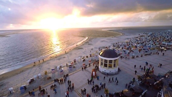 Menschen sind bei Sonnenuntergang an einem Strand. © NDR 