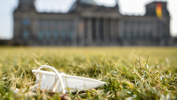 Eine FFP2-Maske liegt auf der Wiese vor dem Deutschen Bundestag. © picture alliance/dpa/dpa-Zentralbild Foto: Kira Hofmann