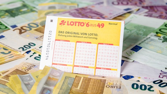 Ein Lottoschein, darunter Geldscheine (gestellte Szene). © picture alliance/Fotostand/K. Schmitt Foto: K. Schmitt