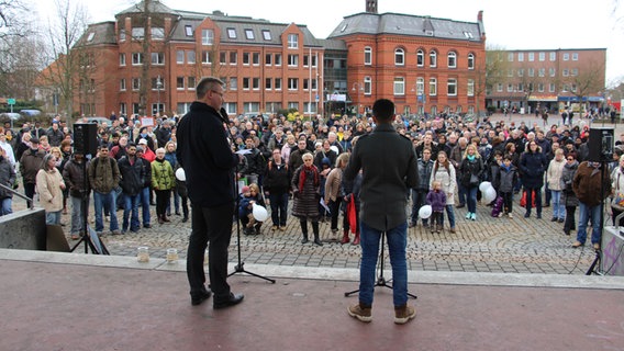 Pastor Markus Kalmbach und Abdullah Abd sprechen zu einer Menschenmenge. © NDR Foto: Christian Berndt