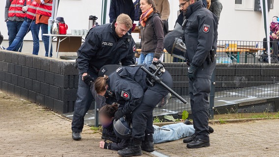Polizisten stehen während der Demonstration gegen den AfD-Parteitag, um eine Person, die am Boden liegt. © dpa Foto: Georg Wendt