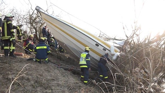 Einsatzkräfte der Feuerwehr stehen um einen verunglücktes Sportboot herum. © NonstopNews 
