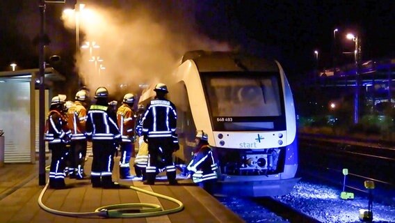 Feuerwehrleute auf einem Bahnsteig vor einem qualmenden Zug © TV-Elbnews 