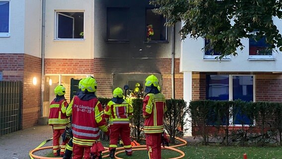 Einsatzkräfte der Feuerwehr stehen vor einem Brand in einem Mehrfamilienhaus in Lüneburg. Einsatzkräfte der Feuerwehr stehen vor einem Brand in einem Mehrfamilienhaus in Lüneburg. © NDR Foto: Carlo Eggeling