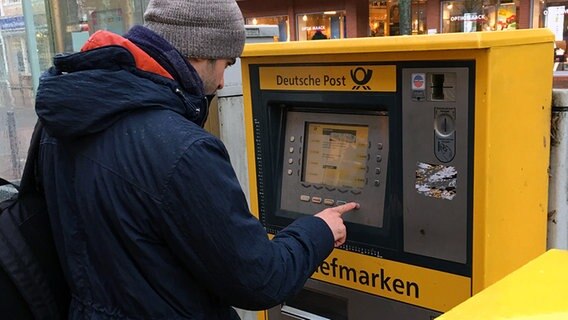 Mohammad Abd zieht sich eine Briefmarke an einem Automaten der Deutschen Post. © Privat 