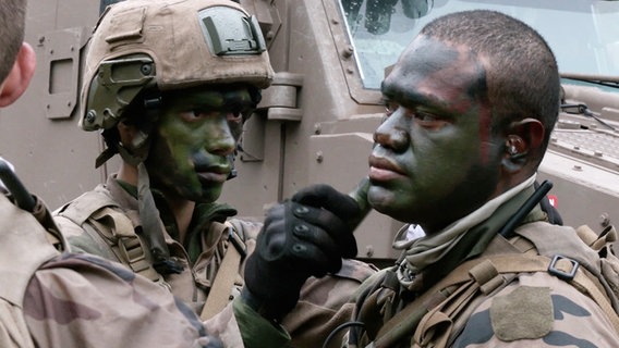Soldaten der binationalen Brigade tarnen ihre Gesichter mit Farbe. © TeleNewsNetwork 