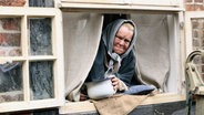 Eine alte Frau guckt aus einem Fenster. © NDR/ Martin Hutcheson Fotograf: Martin Hutcheson