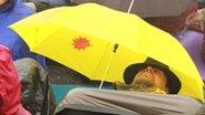 Ein Atomkraft-Gegner schläft unter seinem Regenschirm auf der Straße.  Foto: Harald Ganswindt