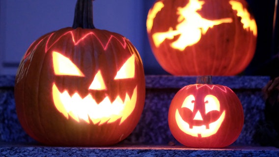 Drei beleuchtete Halloweenkürbisse stehen auf einer Treppe. © dpa Bildfunk Foto: Bernd Weissbrod