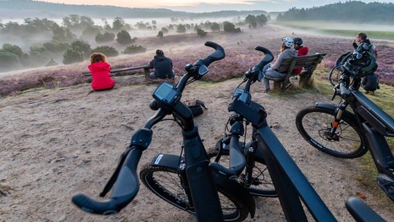 Teilnehmer einer E-Bike-Safari genießen den Sonnenaufgang in der Lüneburger Heide. © dpa-Bildfunk Foto: Philipp Schulze