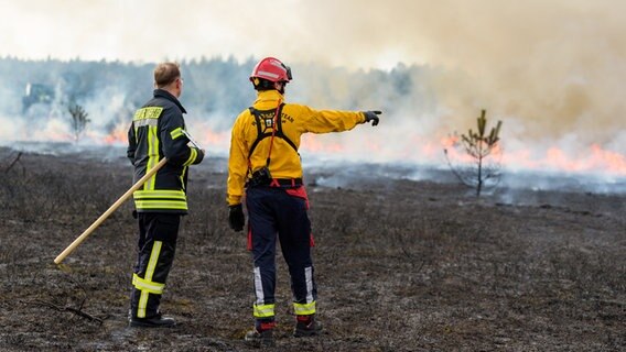 Zwei Feuerwehrleute überwachen das Abbrennen einer Heidefläche. © dpa Foto: Philipp Schulze