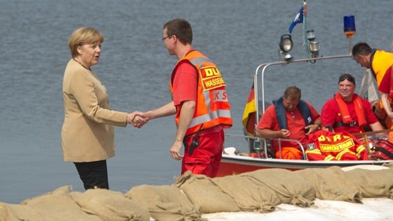 Angela Merkel schüttelt in Hitzacker die Hand eines DLRG-Helfers.  Foto: Sebastian Kahnert