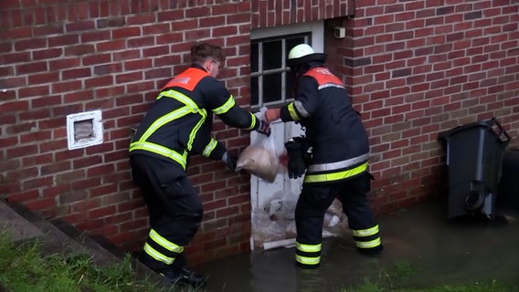 Feuerwehrleute stapeln Sandsäcke an einer Tür. © Hellwig TV-Elbnews Produktion 