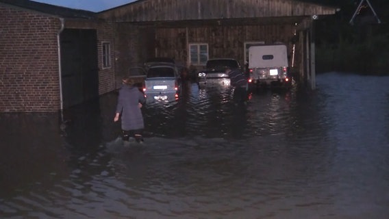 Zwei Menschen laufen über einen überschwemmten Hof. © Hellwig TV-Elbnews Produktion 